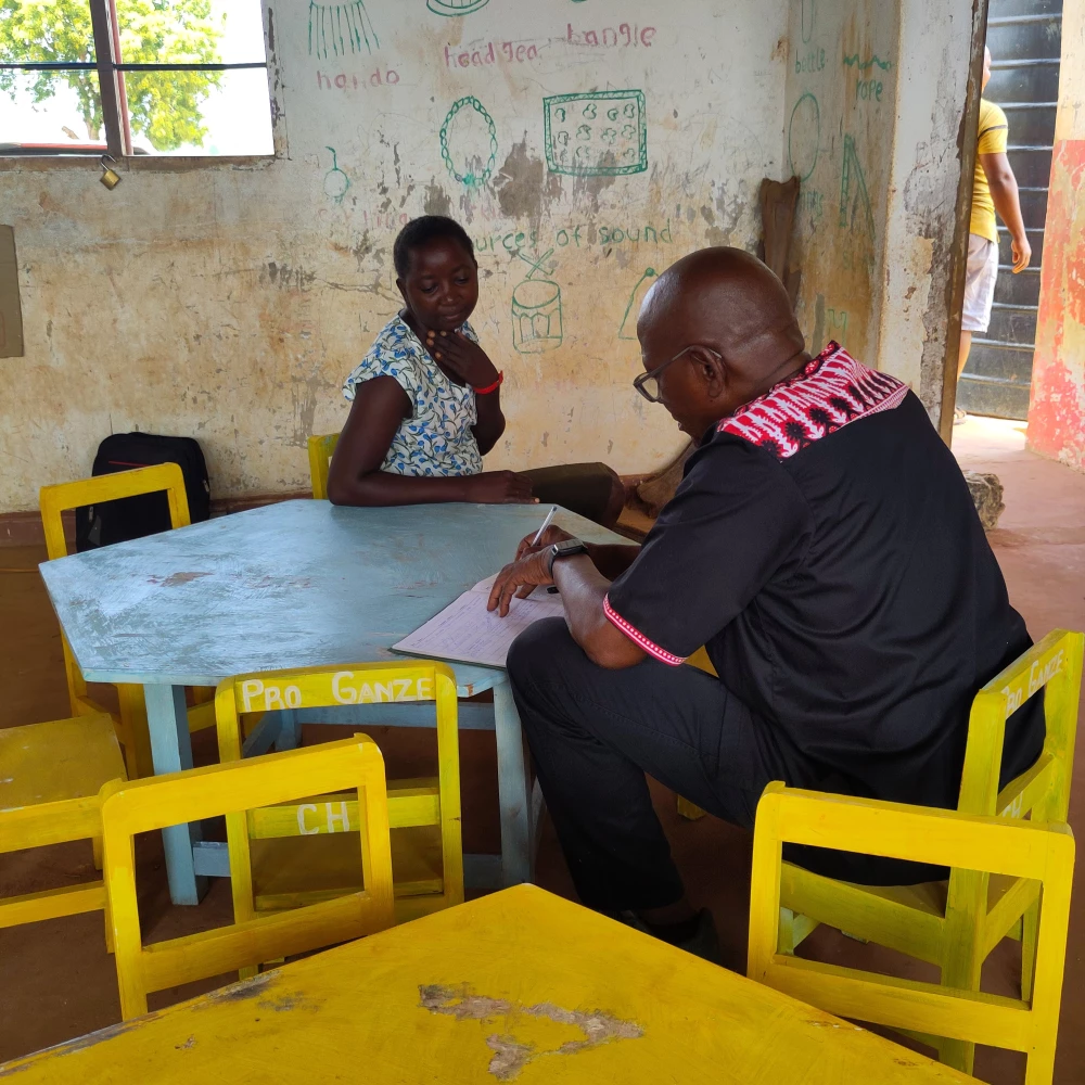 Peter Safari Shehe trägt sich im Schulgästebuch ein.