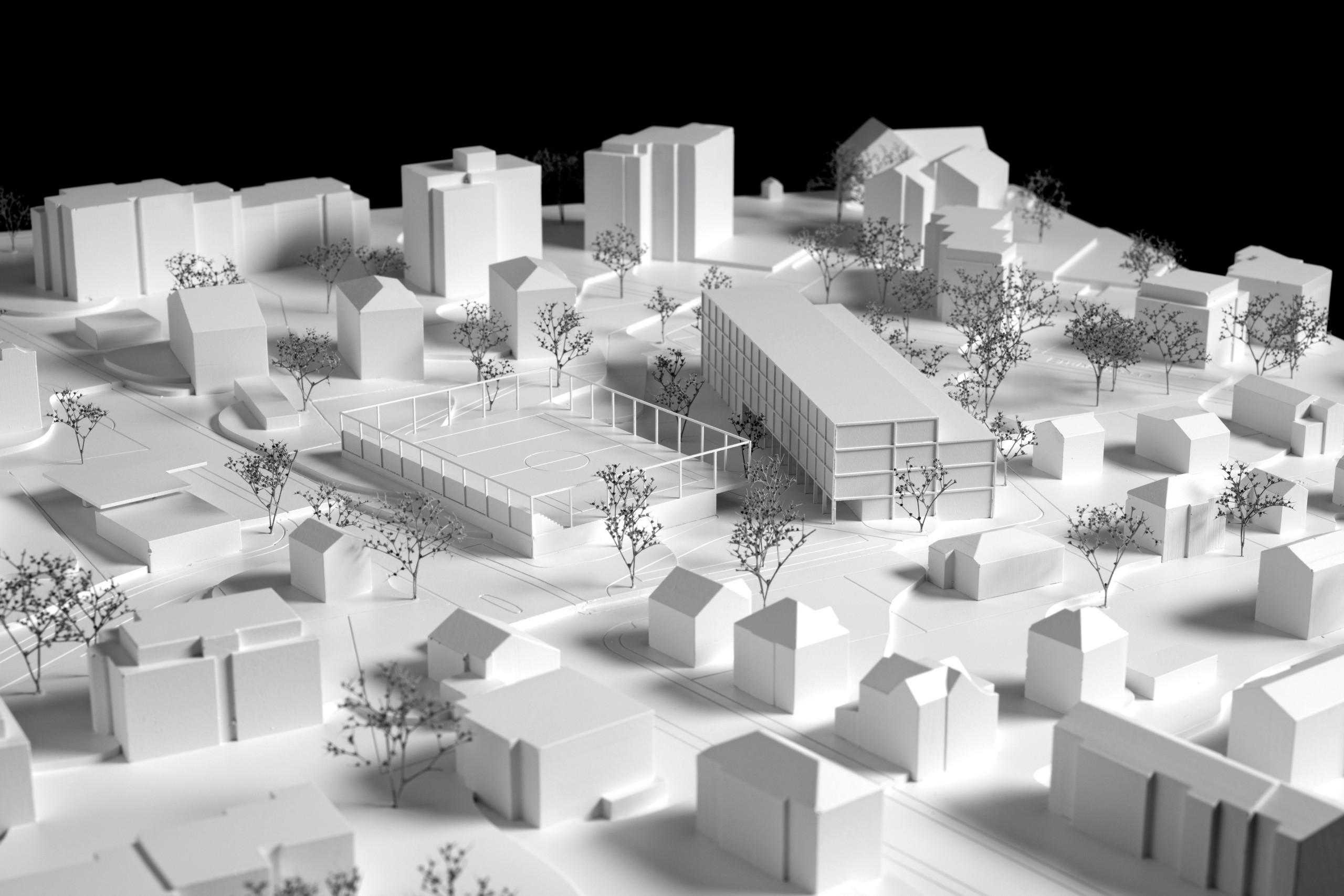Das Modell zeigt die geplante Dreifach-Turnhalle mit dem Allwettersportplatz auf deren Dach (1), sowie den Schulhaus-Neubau rechts davon (2).